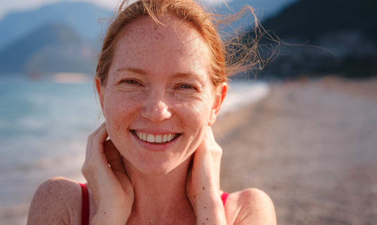 Frau am Strand mit natürlichem Sonnenschutz - strahlend und geschützt